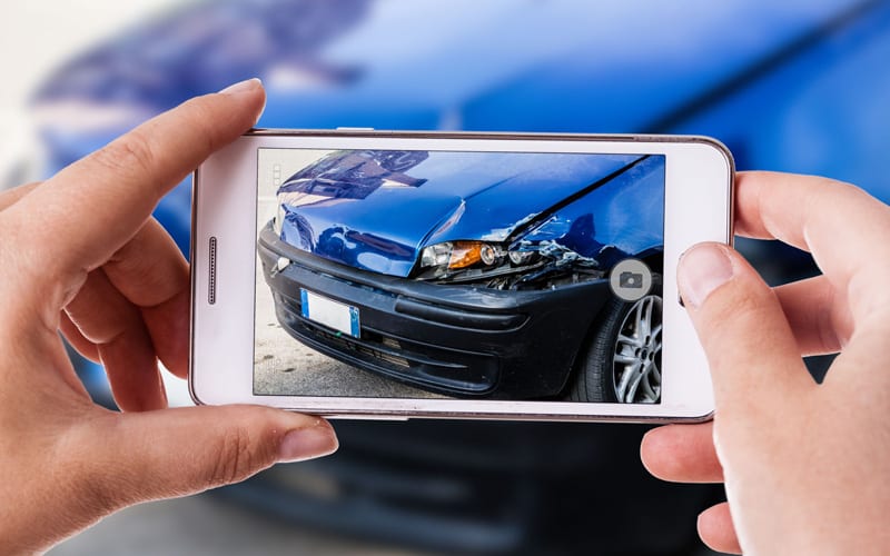 Insurance adjuster holding mobile taking photo of accident