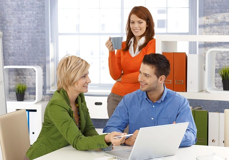 Two females and male meeting in front of a laptop